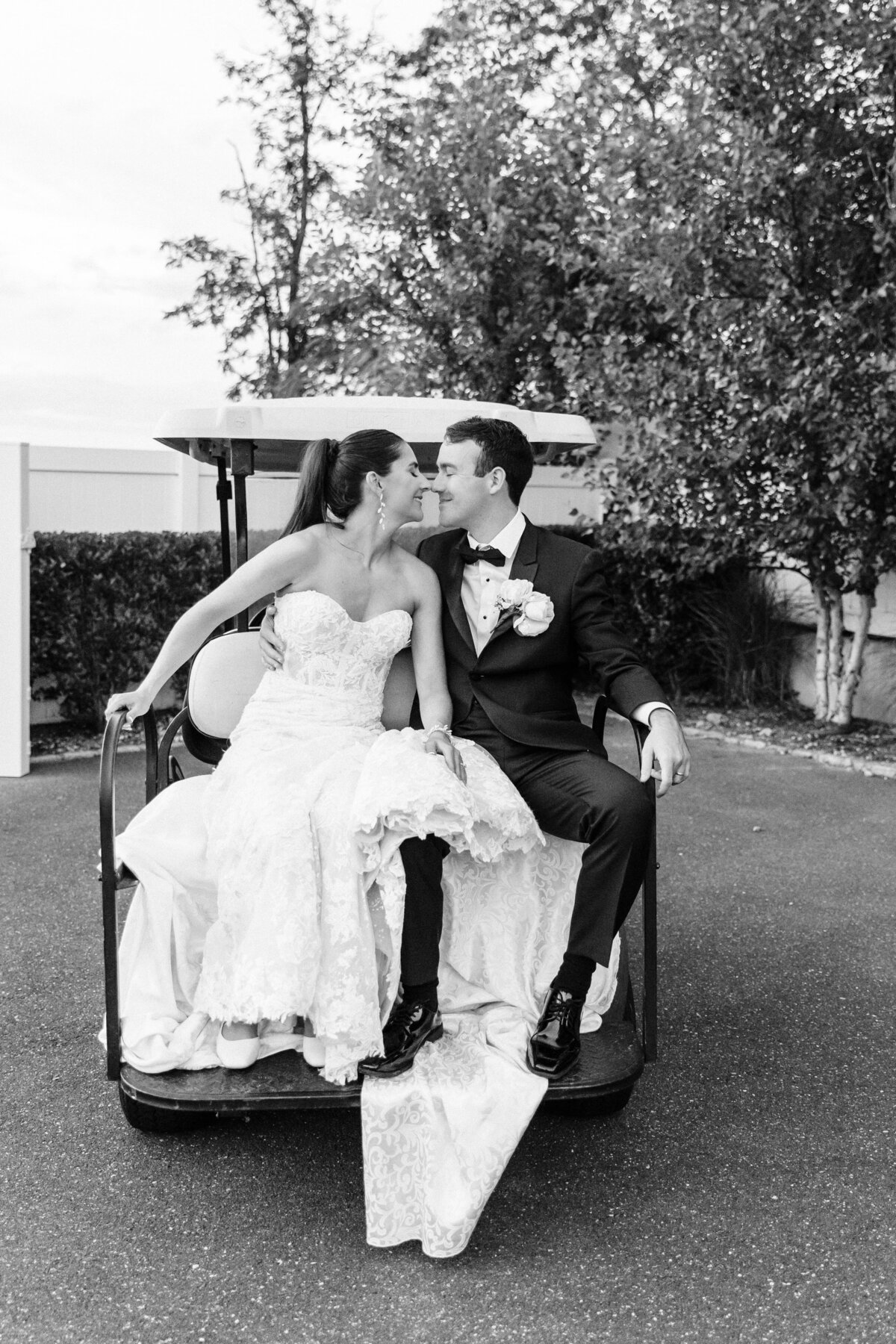 Bride and groom sitting on back of gold cart at Long Island wedding