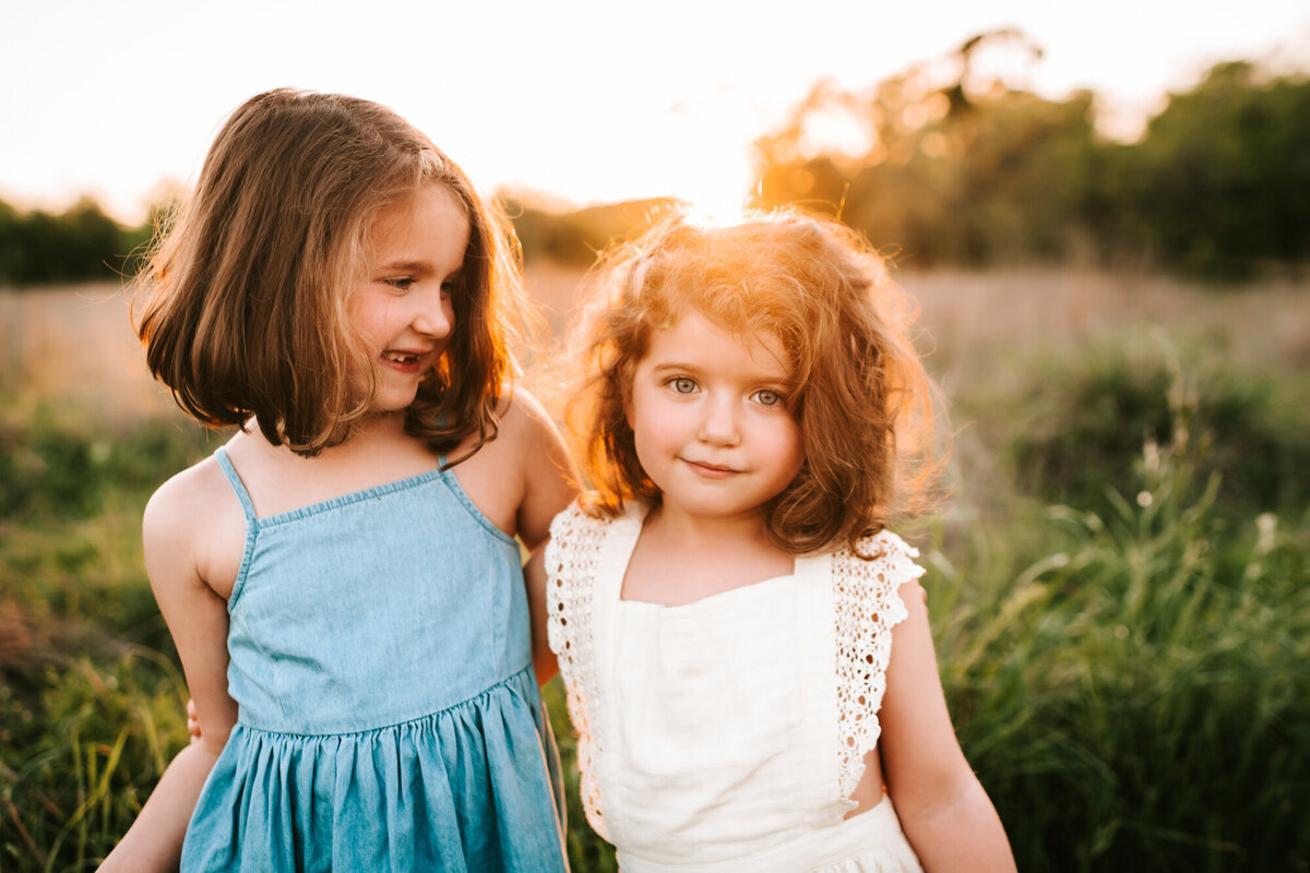 Family Photography, Two sisters hugging in the field at sunset.