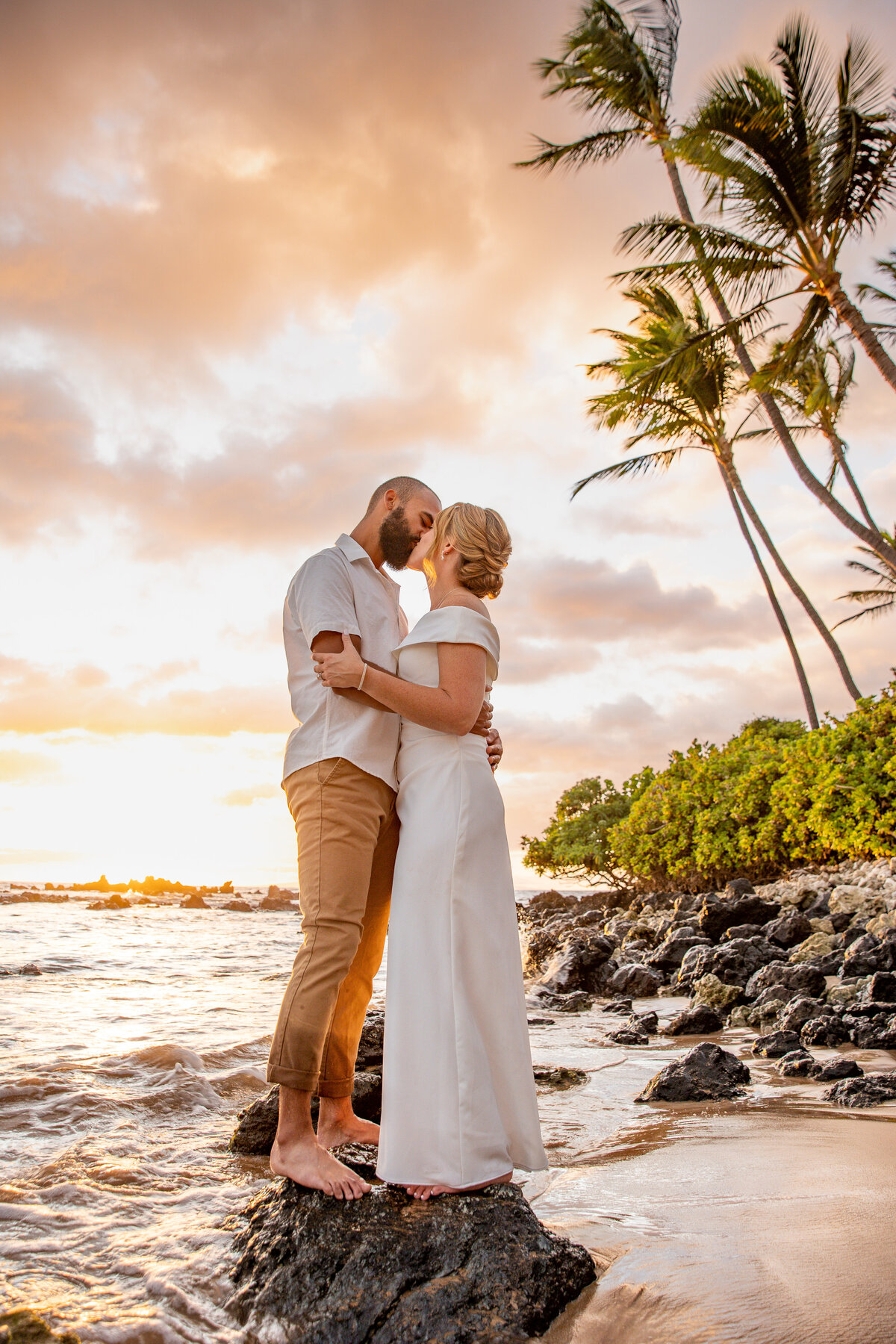 Maui Wedding Photographer captures bride and groom embracing at sunset on rocks