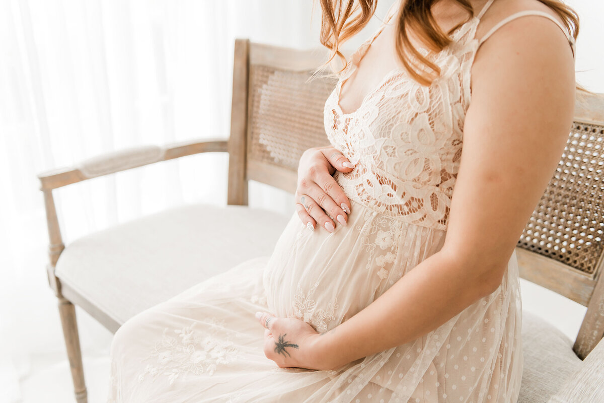 A pregnant woman posing for a photo in a lace dress with destin fl family photographers.