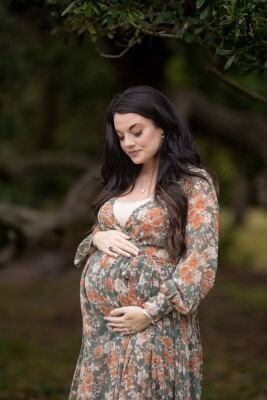 Pregnant woman in floral dress during outdoor maternity photo session by professional St Augustine maternity photographers