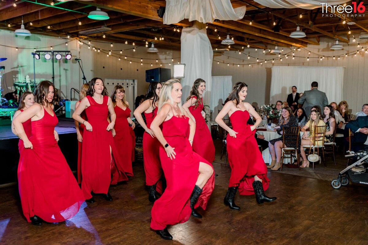 Bridesmaids do a line dance together in their red dresses and black cowgirl boots