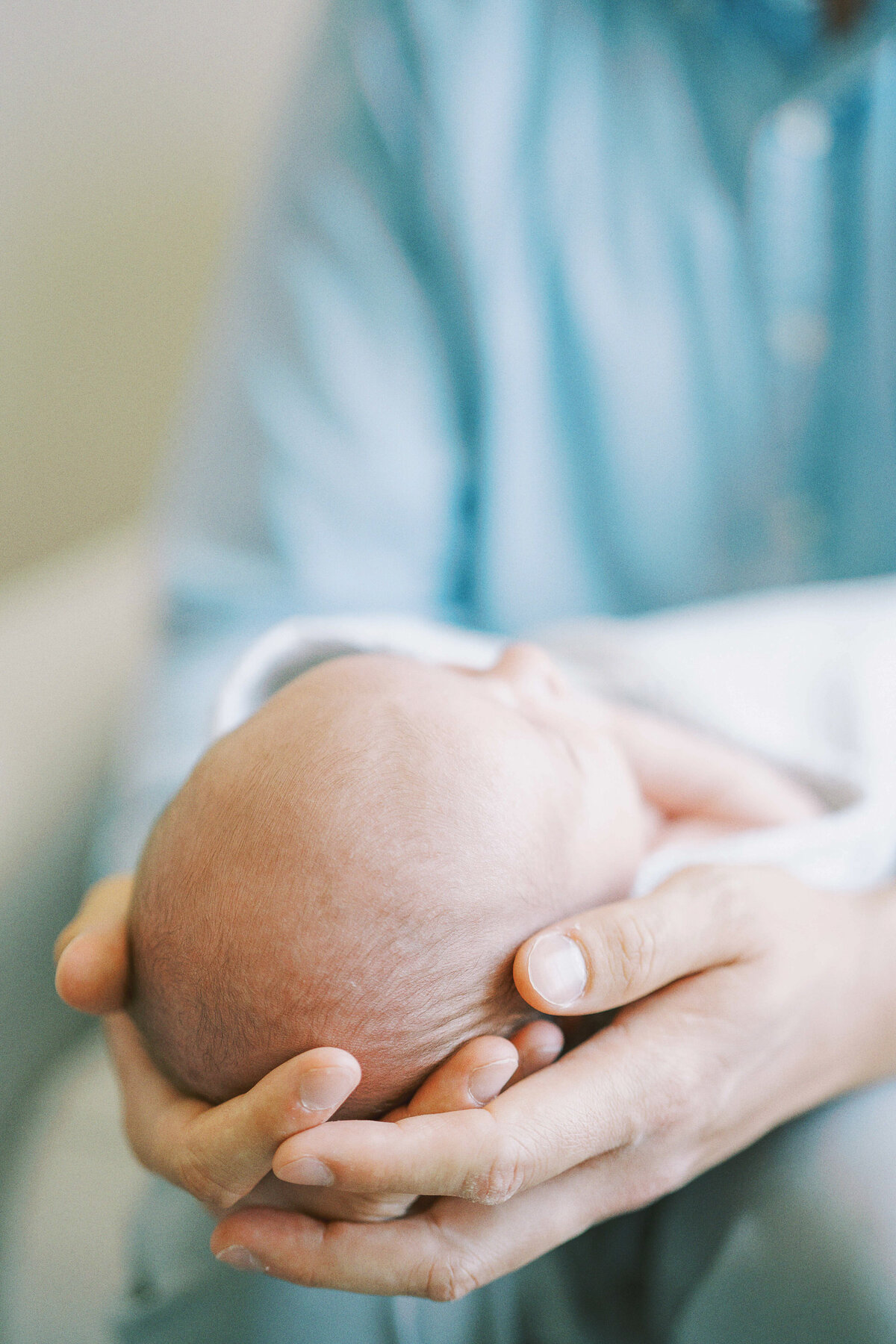 close up photo of wrinkles on baby's head while dad holds him in his hands