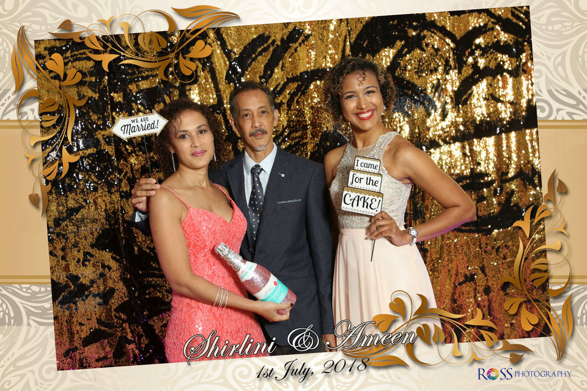 Man and two women hold signs in photobooth. Photobooth by Ross Photography, Trinidad, W.I..