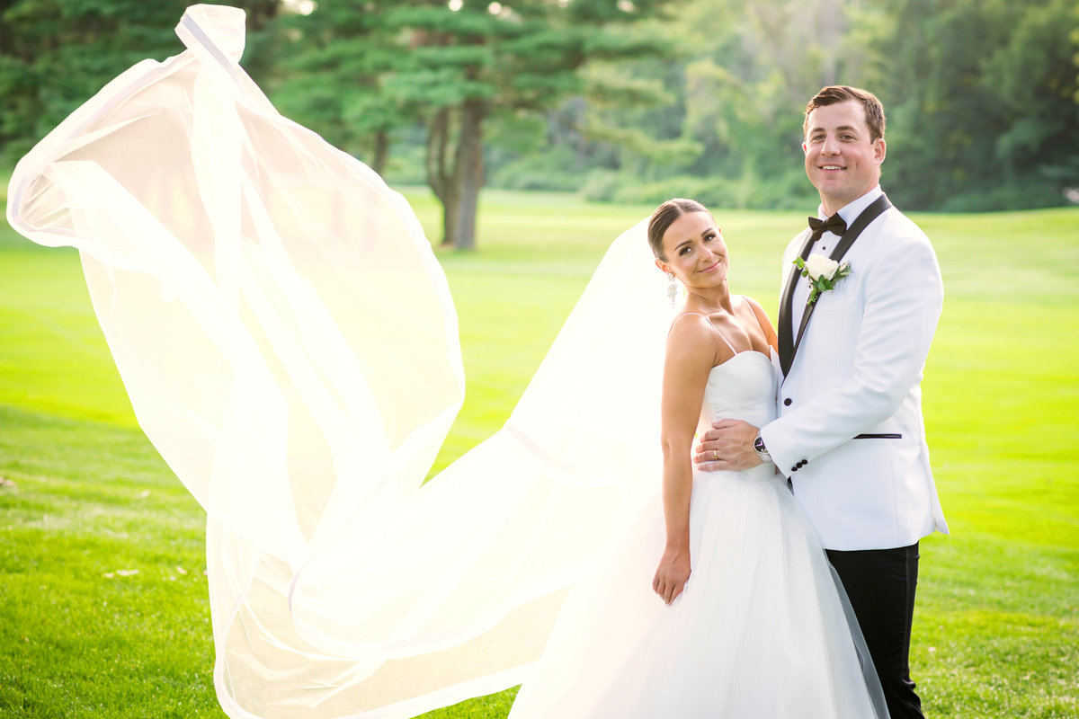 groom holding his bride photo on the green fairways at The Muttontown Club