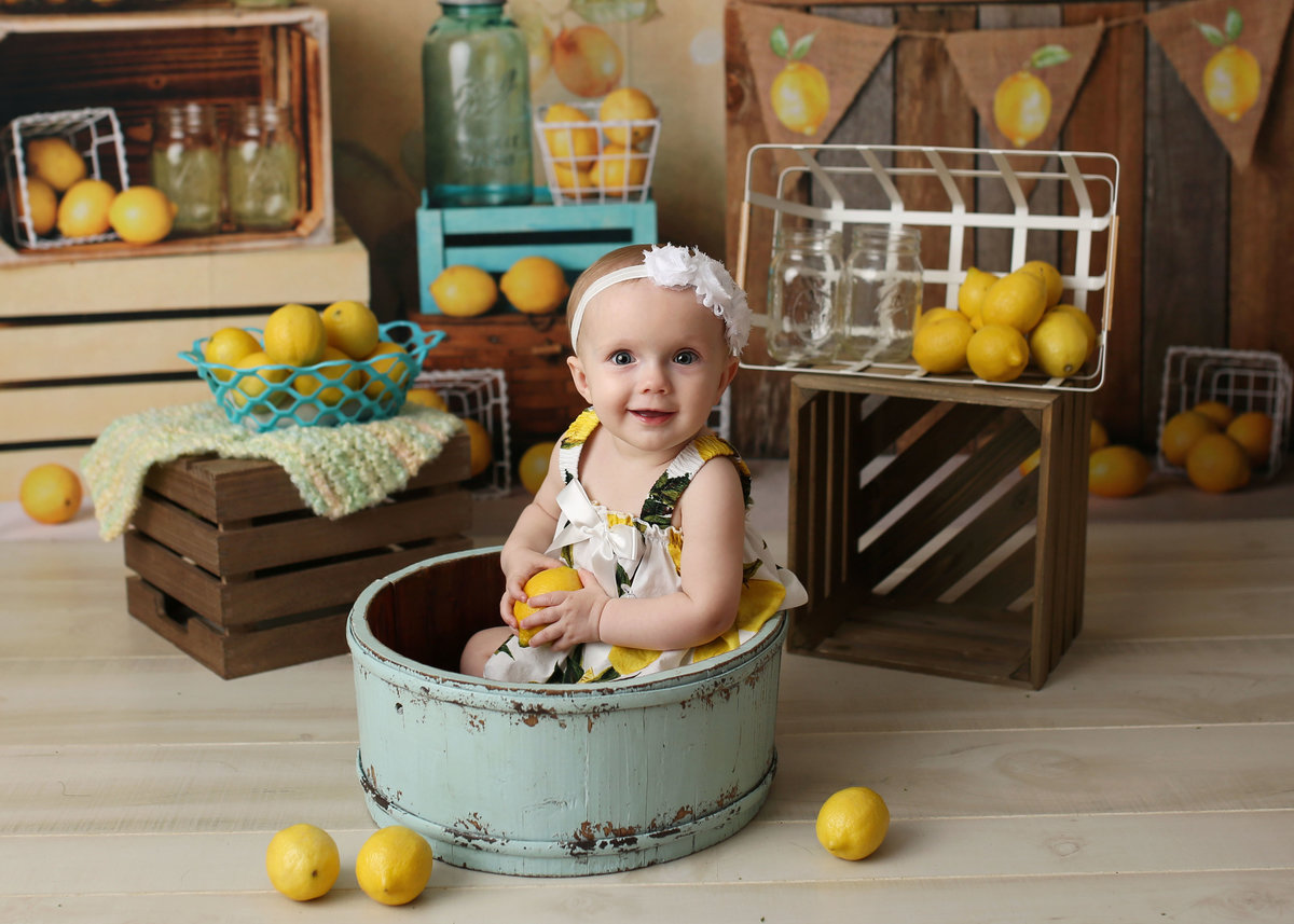 baby girl lemonade stand setup posed in antique wash bucket