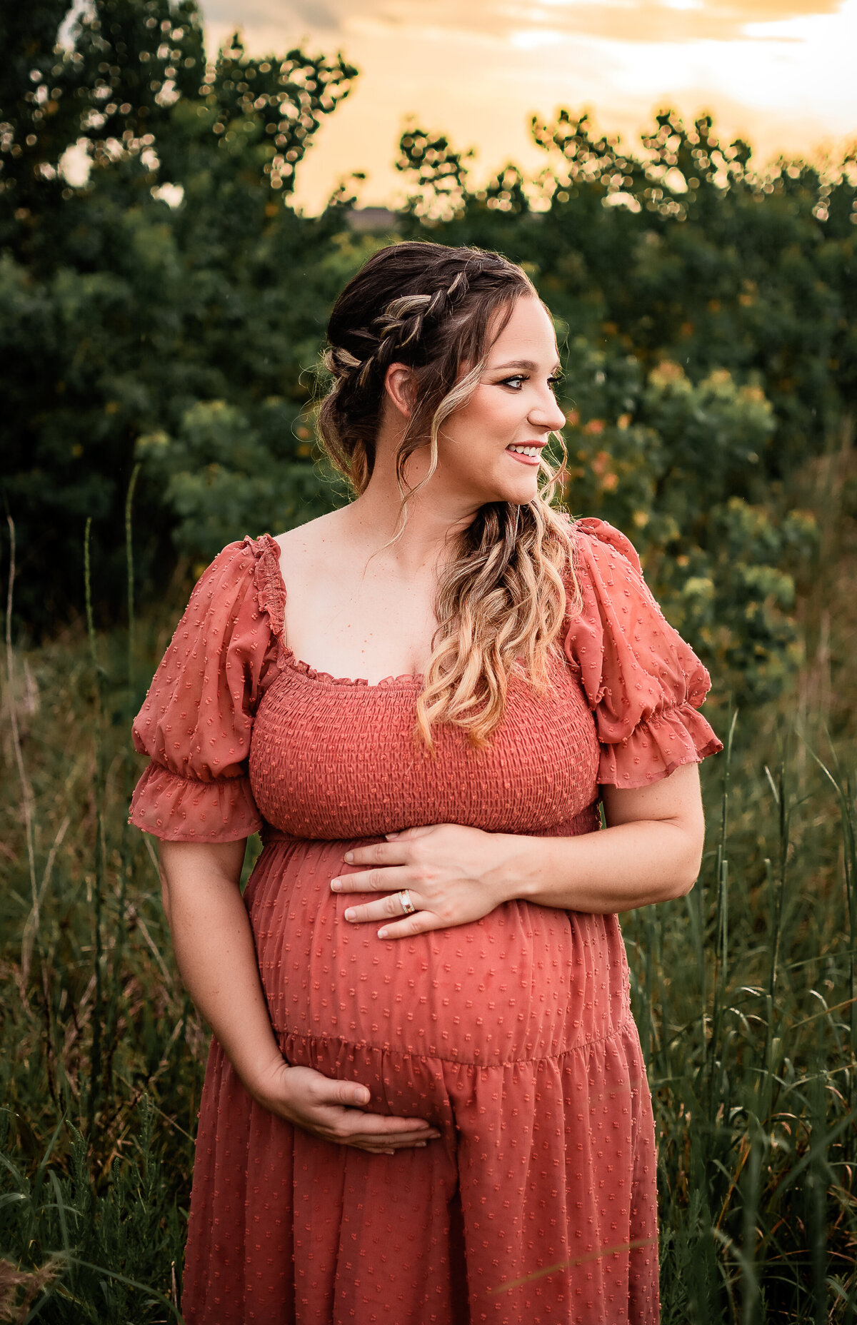 A Houston area mom to be holds her belly and smiles to her left.