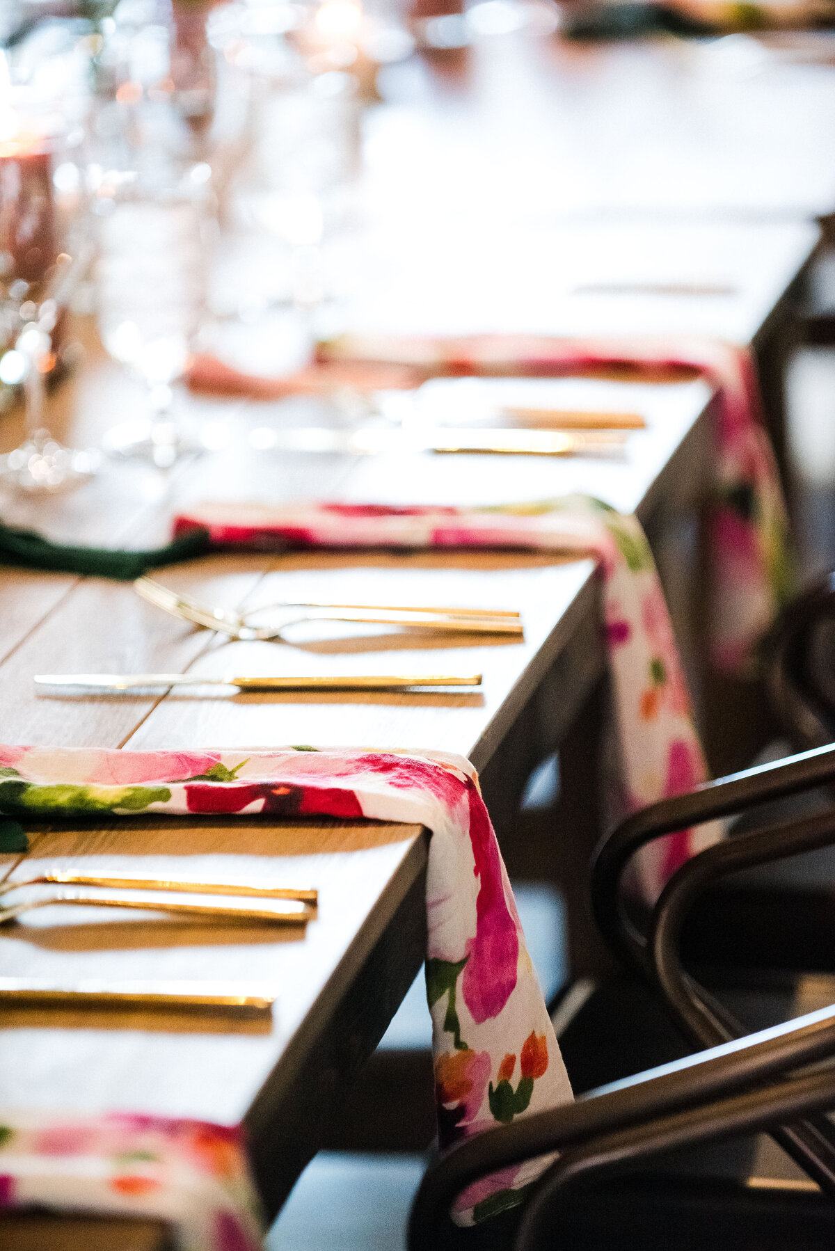 A close up shot of floral cloth wedding napkins set at each place along a rectangular table.