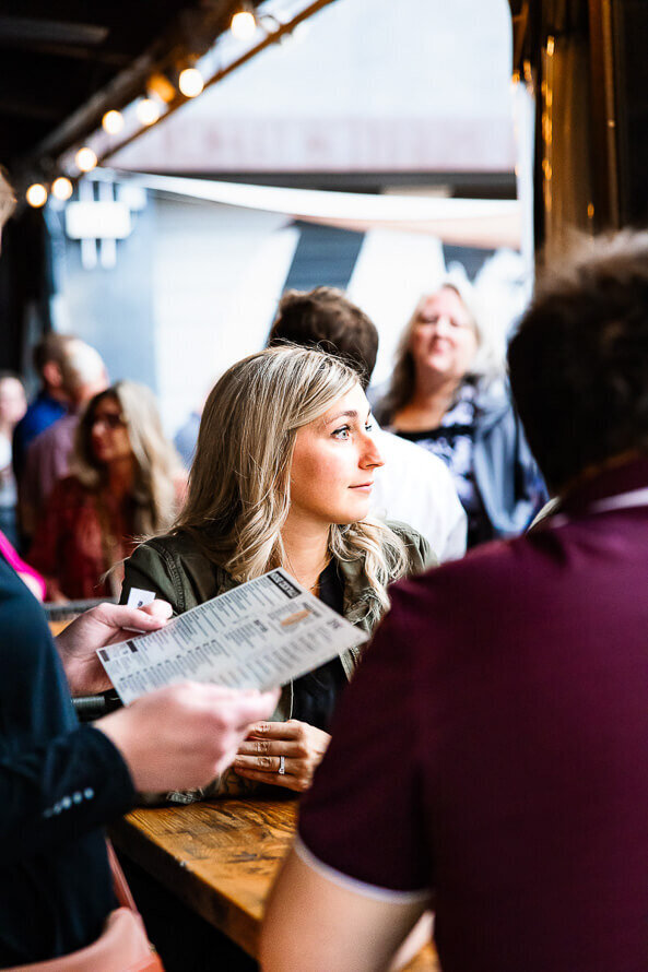 Girl looks off to side while someone looks at a menu in the foreground.