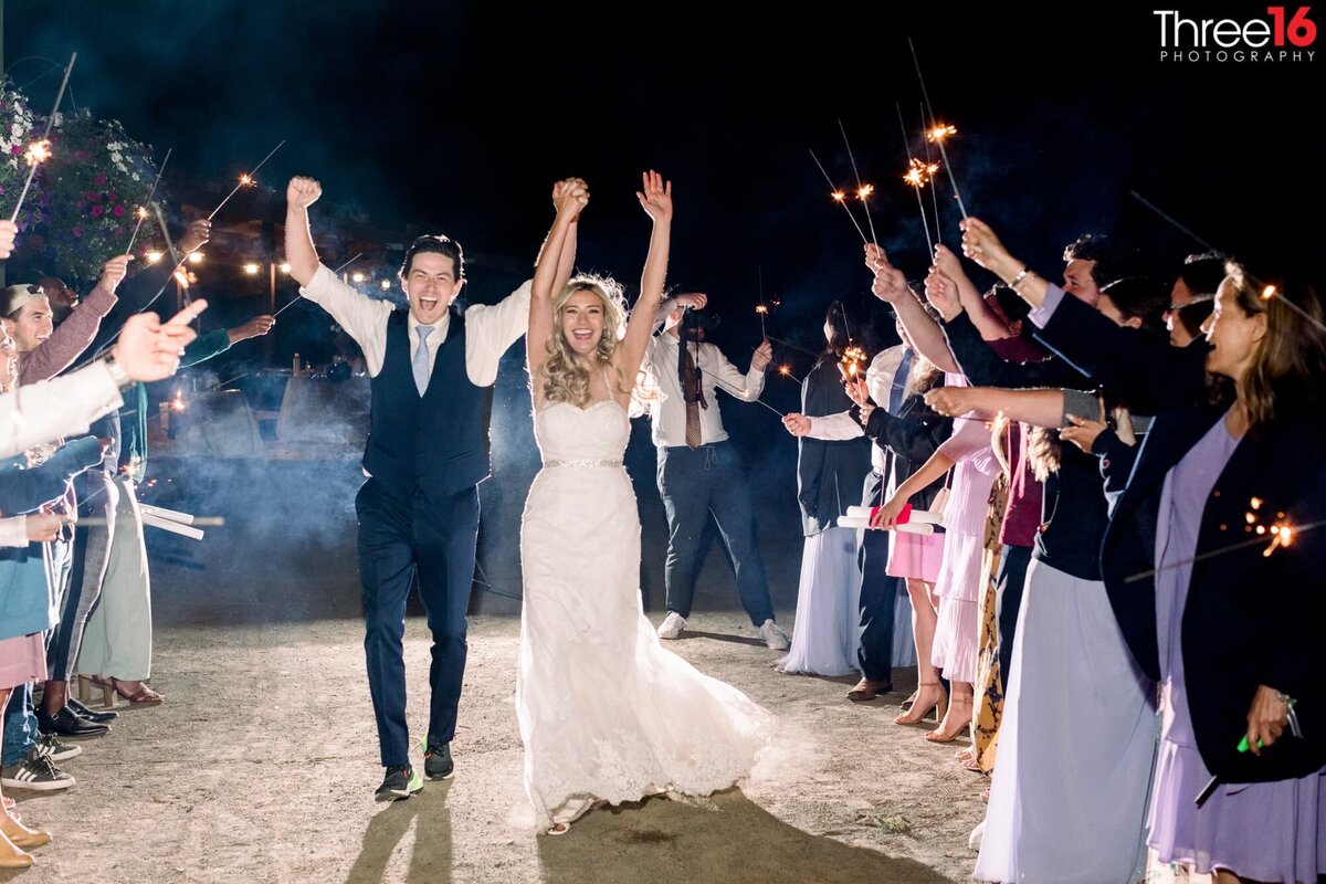 Bride and Groom walk through sparkler carrying wedding guests in celebration of their wedding