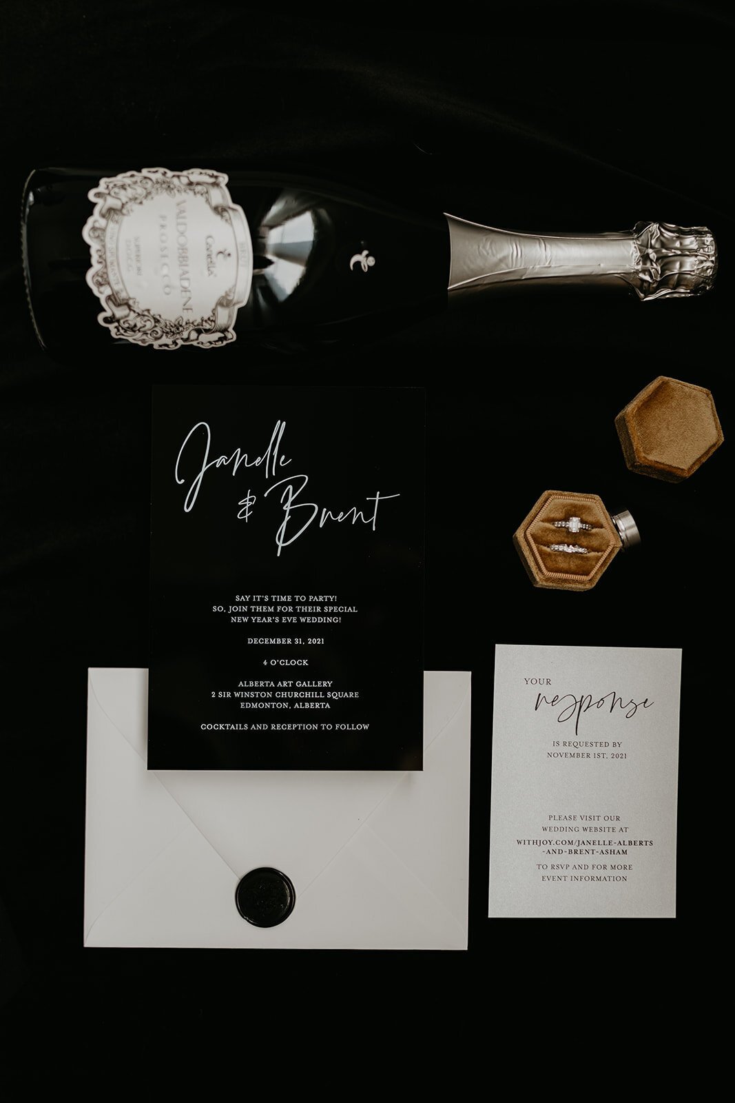 Flat lay of bride's ring with wedding invitation and bottle of champagne.