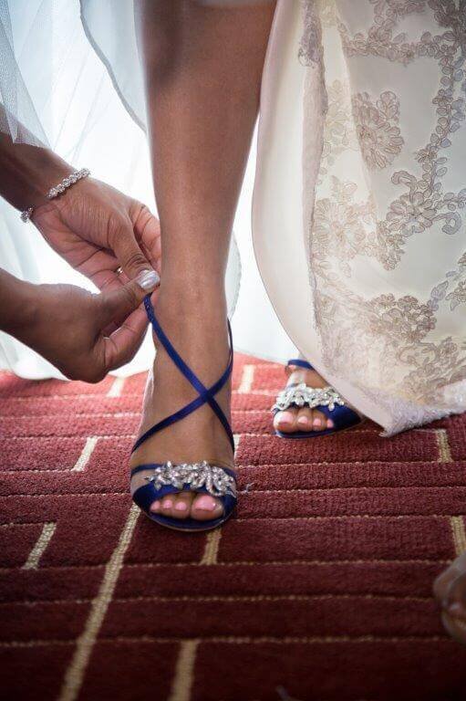 Hands of someone securing brides stilettos before she walks down the aisle.