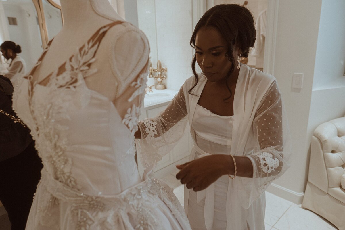 Joy admires her dress on a dressform before she puts it on to be married.