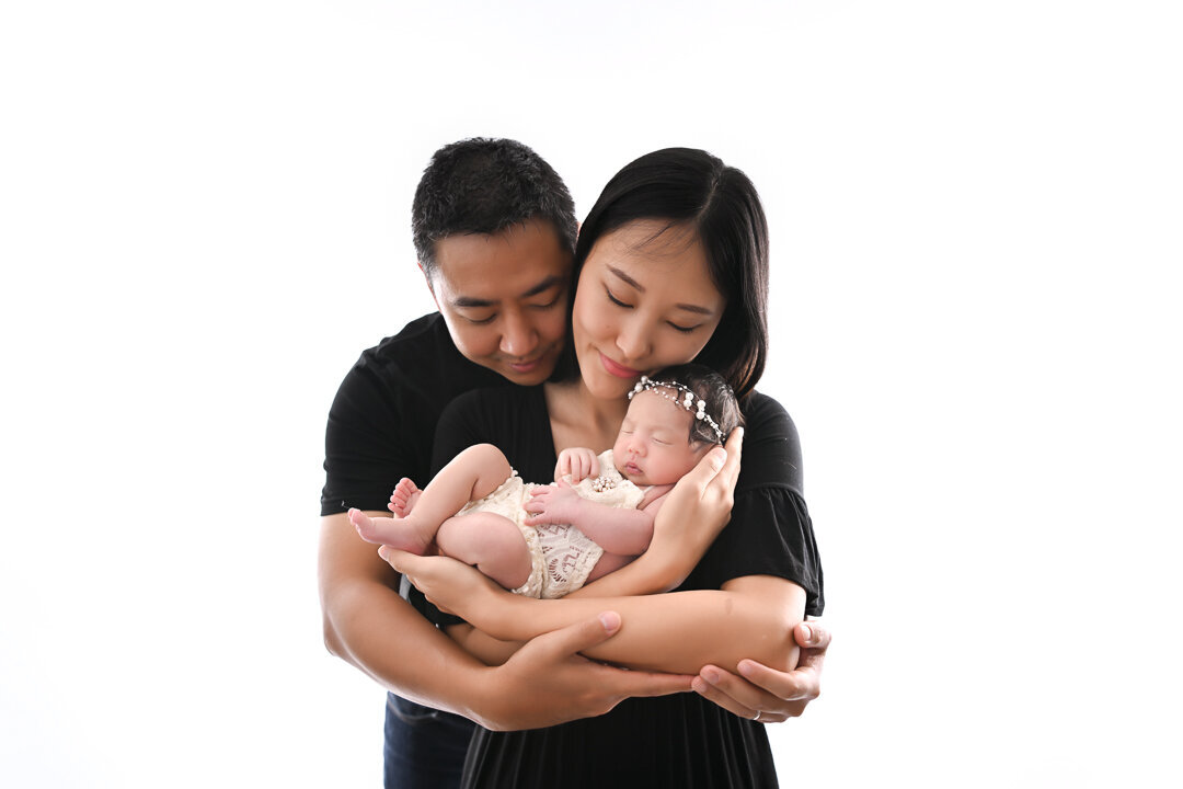 Backlit photo pf mother and father holding newborn baby