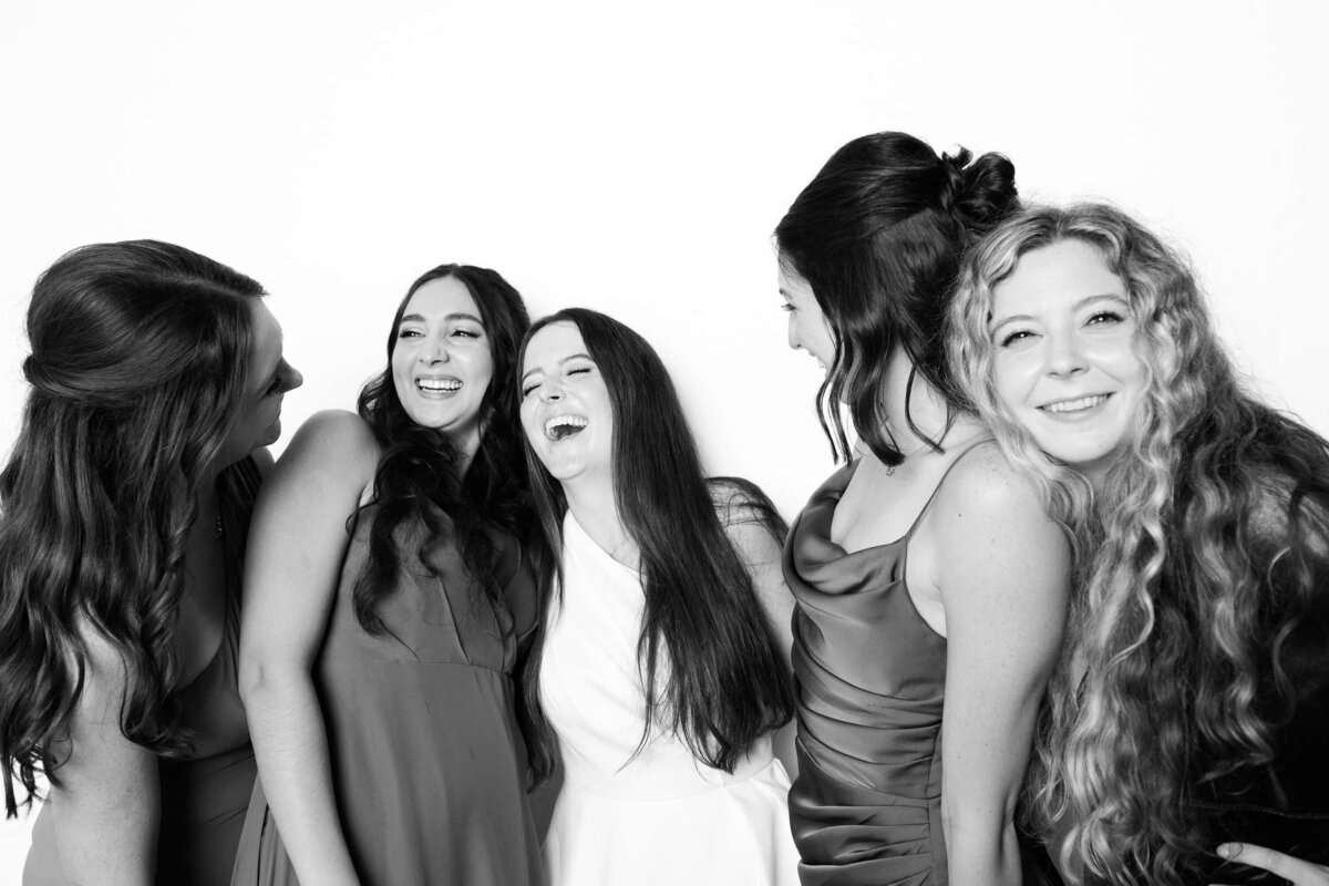 Five women laughing together during a black and white portrait session, captured by Monochrome Portraits—an elevated photo booth experience in Phoenix.