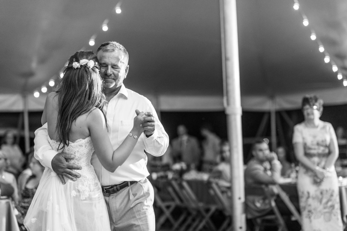 Father and daughter dance under the tent as mom looks on from the side.
