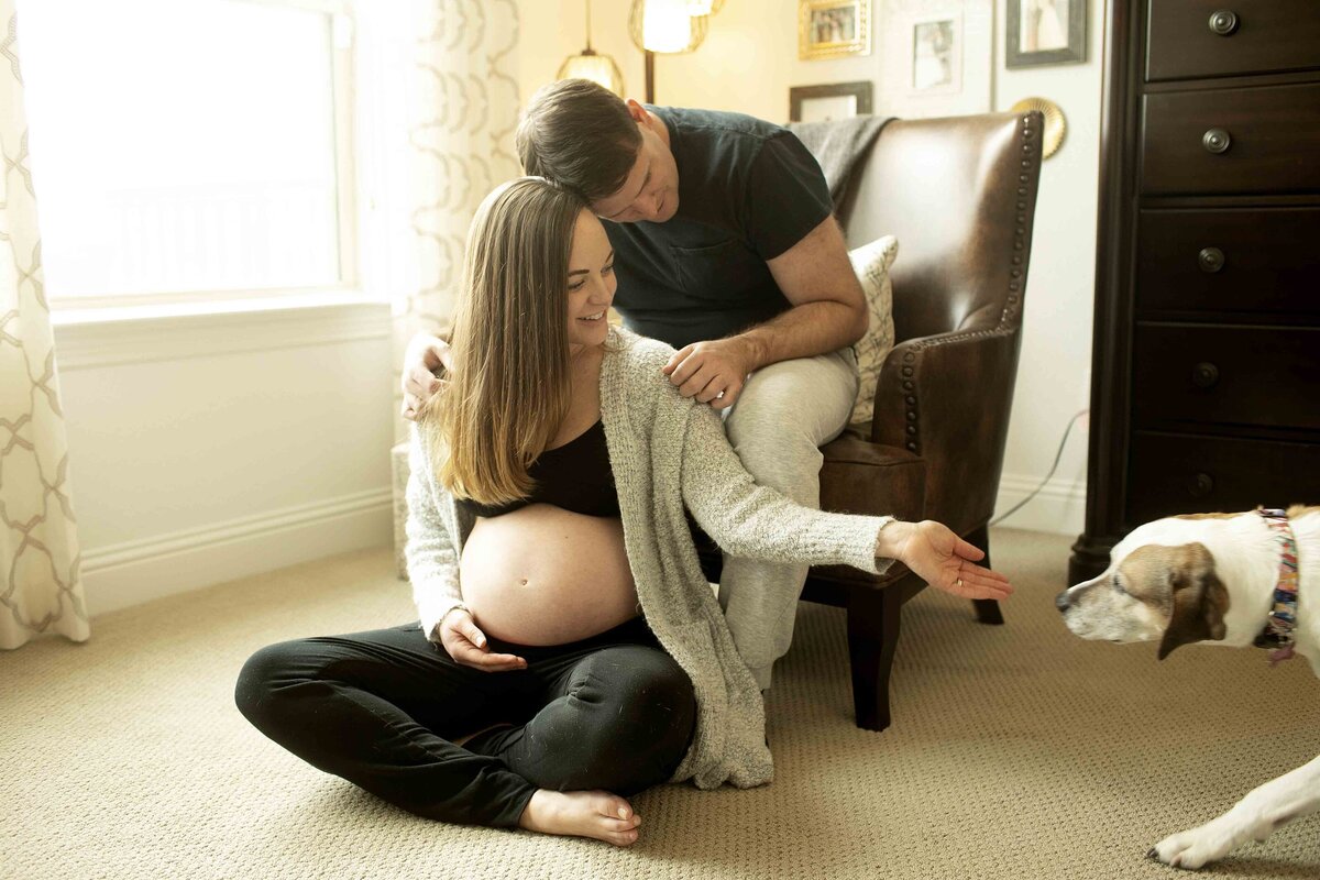 A tender maternity photo of mom and dad in the bedroom, with mom cradling her baby bump while dad gently kisses her forehead, creating a peaceful and intimate moment, captured by Chunky Monkey Photography.