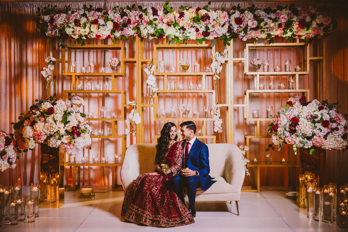 Indian bride and groom at the Marigold in New Jersey sitting on their wedding reception stage having a drink 