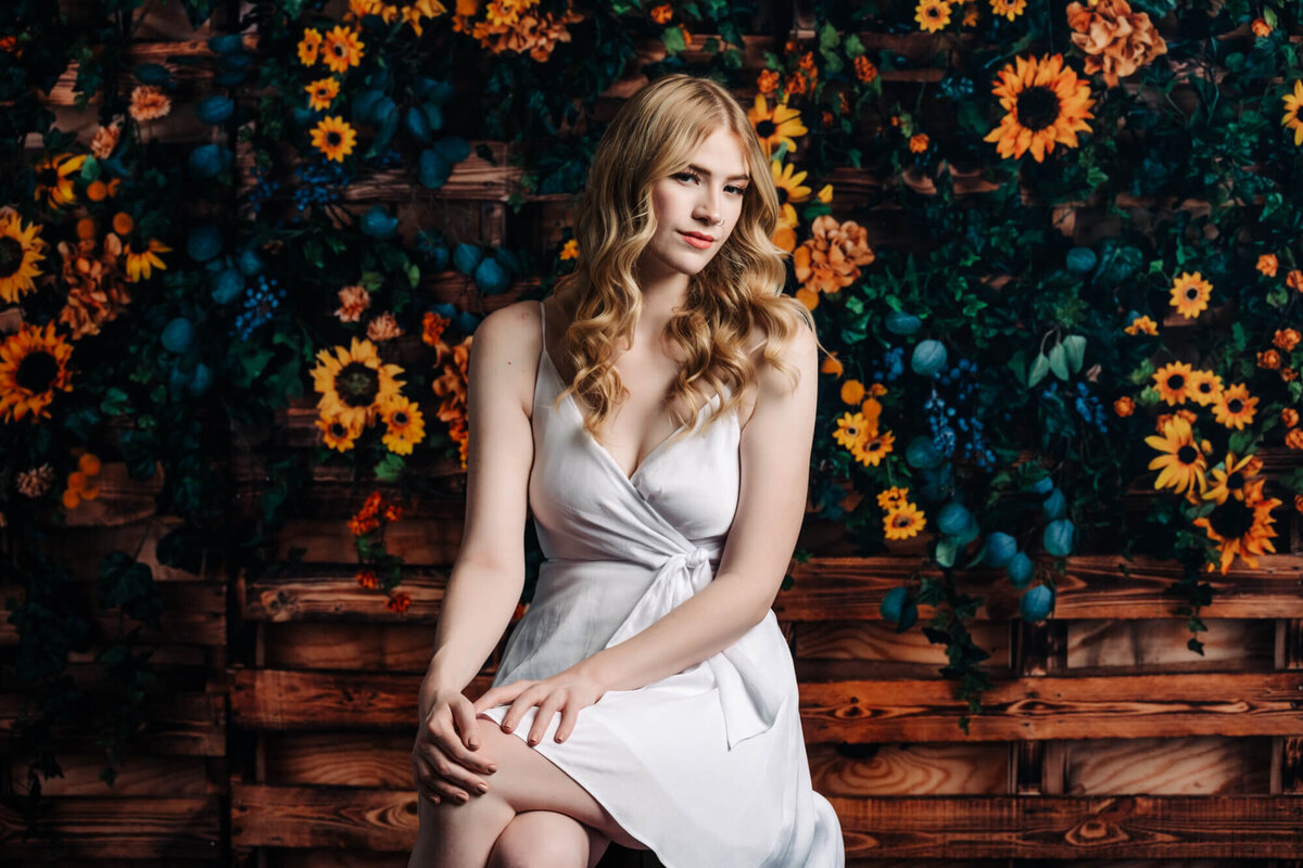 Girl poses on bench in front of flowers in Prescott senior photos by Melissa Byrne