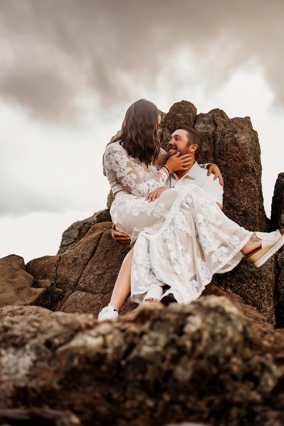 a couple dressed in white and cream colored clothing embrace on a mountain side in Colorado for couples portraits