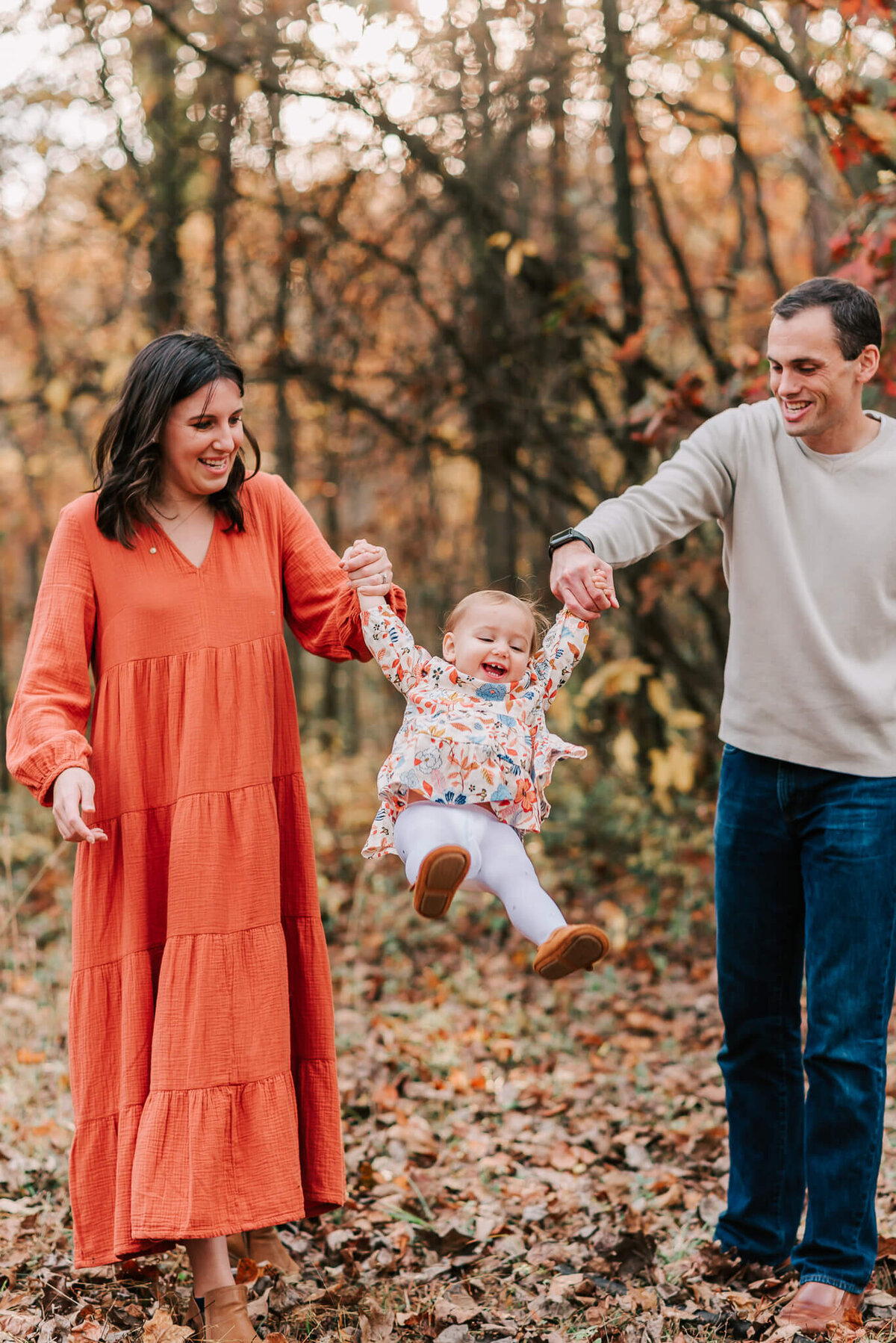 A couple swinging their child by the arms gleefully during their family session in northern Virginia