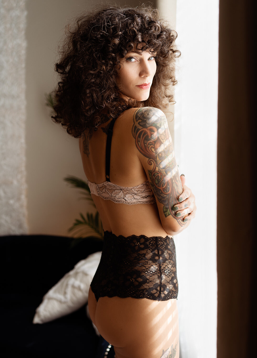 sexy woman with tattoos standing by a window