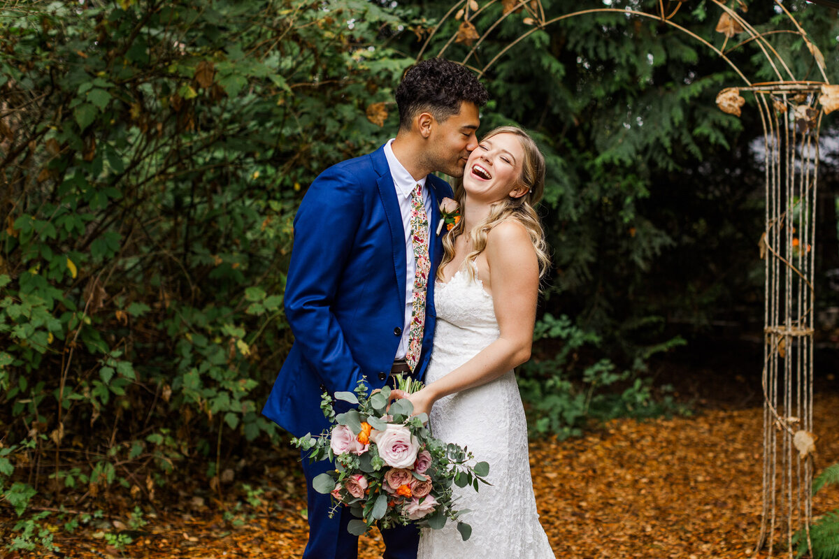 Groom-kisses-bride-at-woodland-wedding-venue-Twin-Wilow-Gardens-in-Snohomish-photo-by-Joanna-Monger-Photography-