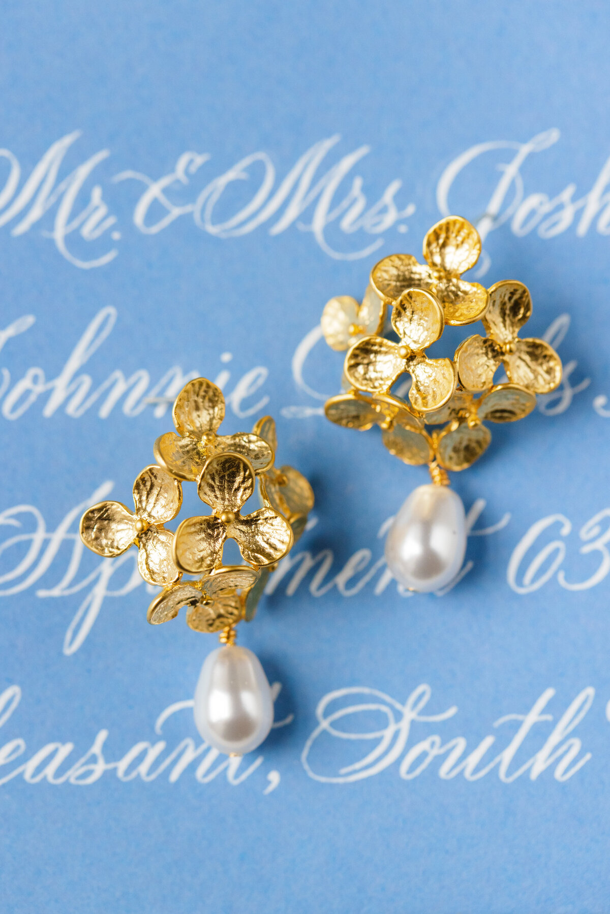 gold and pearl floral earrings styled on calligraphed envelope