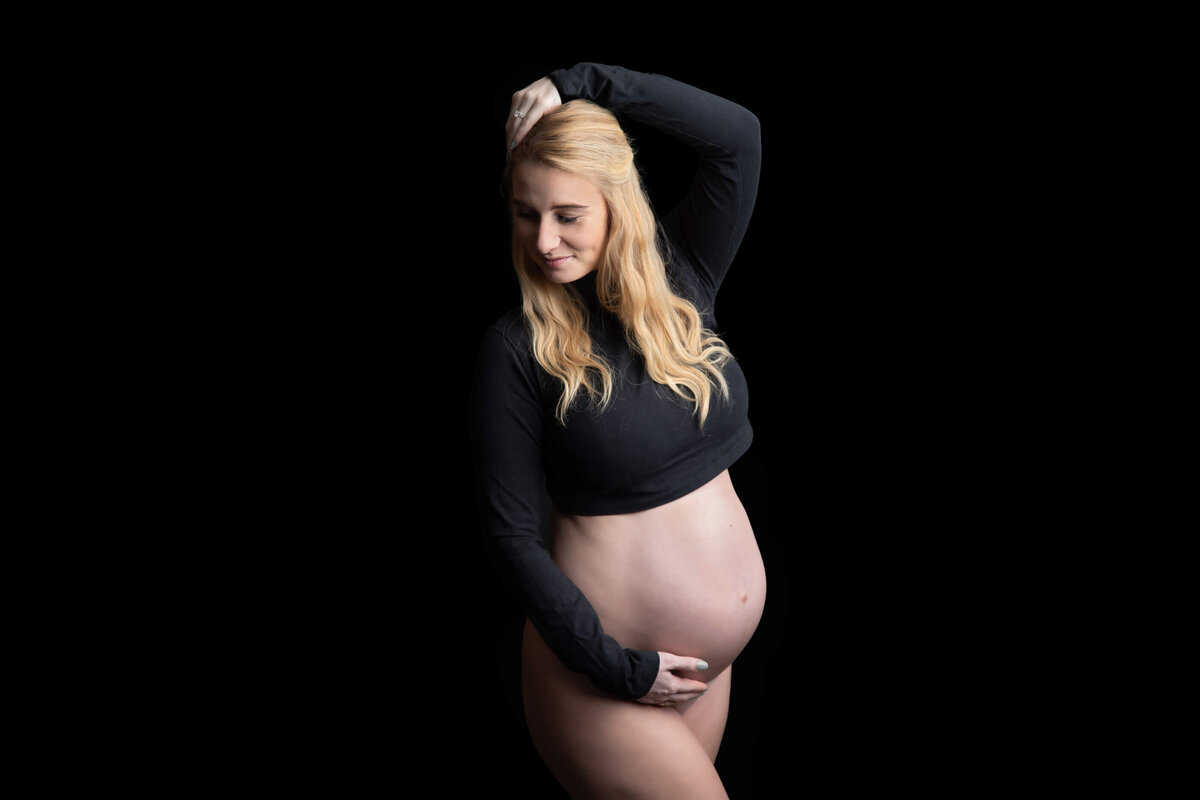 woman wearing a black crop top for her in-studio maternity photos