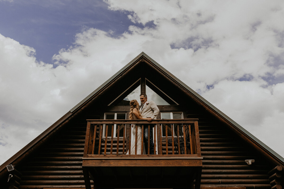 bride and groom standing together on a balcony of a cabin
