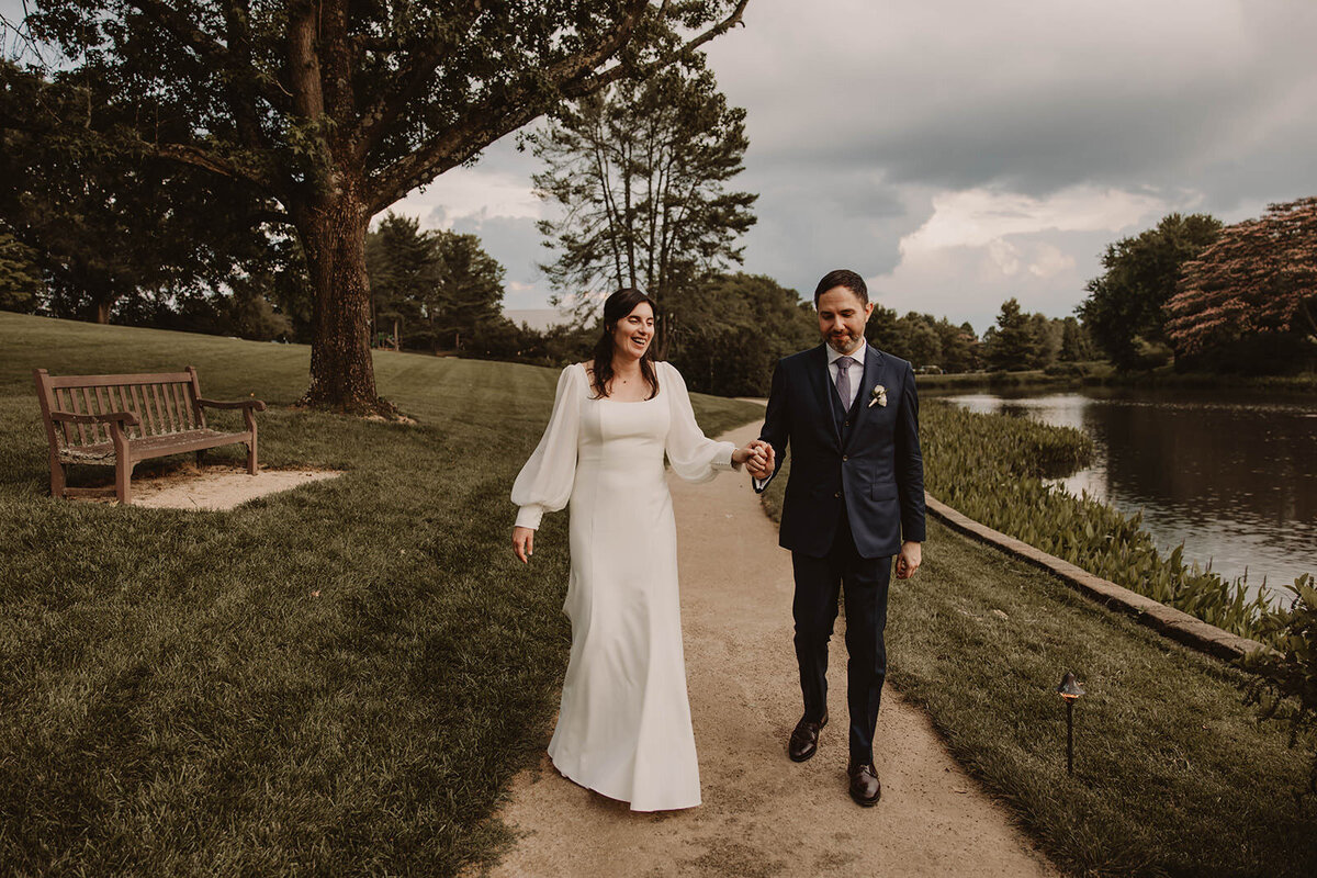 A wedding couple walking together on a dirt path 