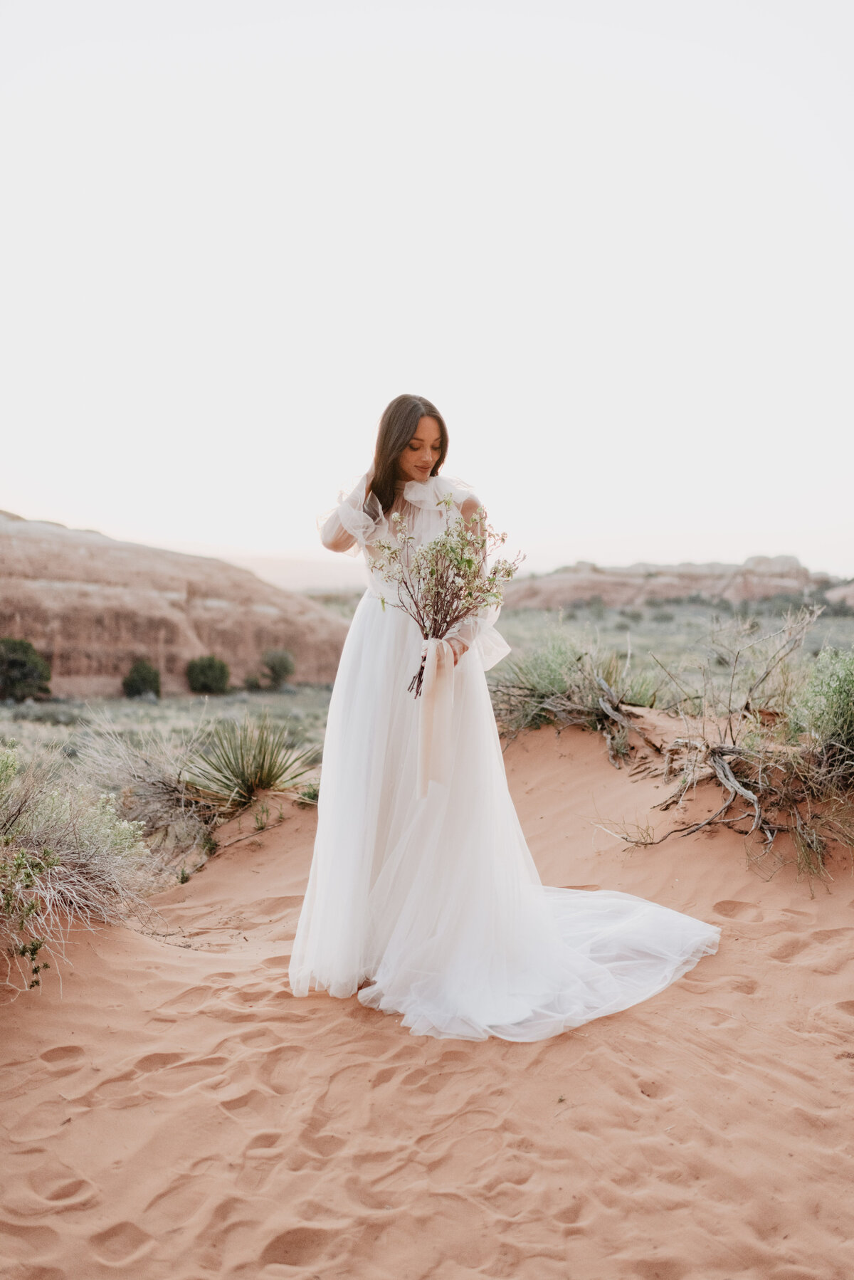 Utah elopement photographer captures bride looking at bouquet during portraits