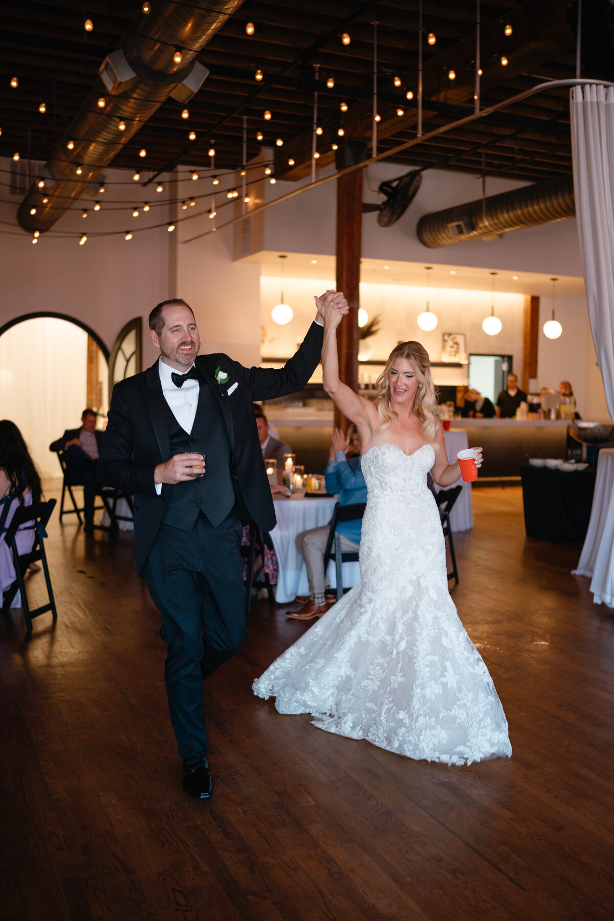 Bride and Groom entering their reception holding their hands up in the air