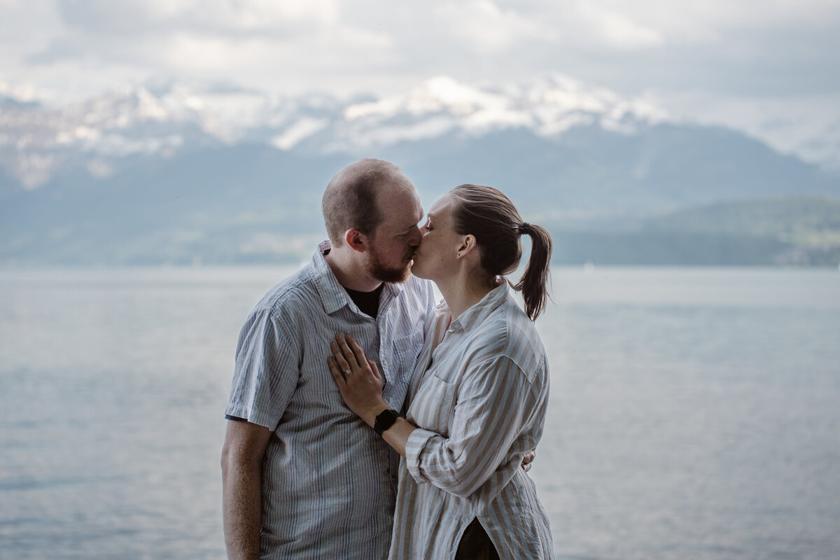 A couple kissing in front of a lake