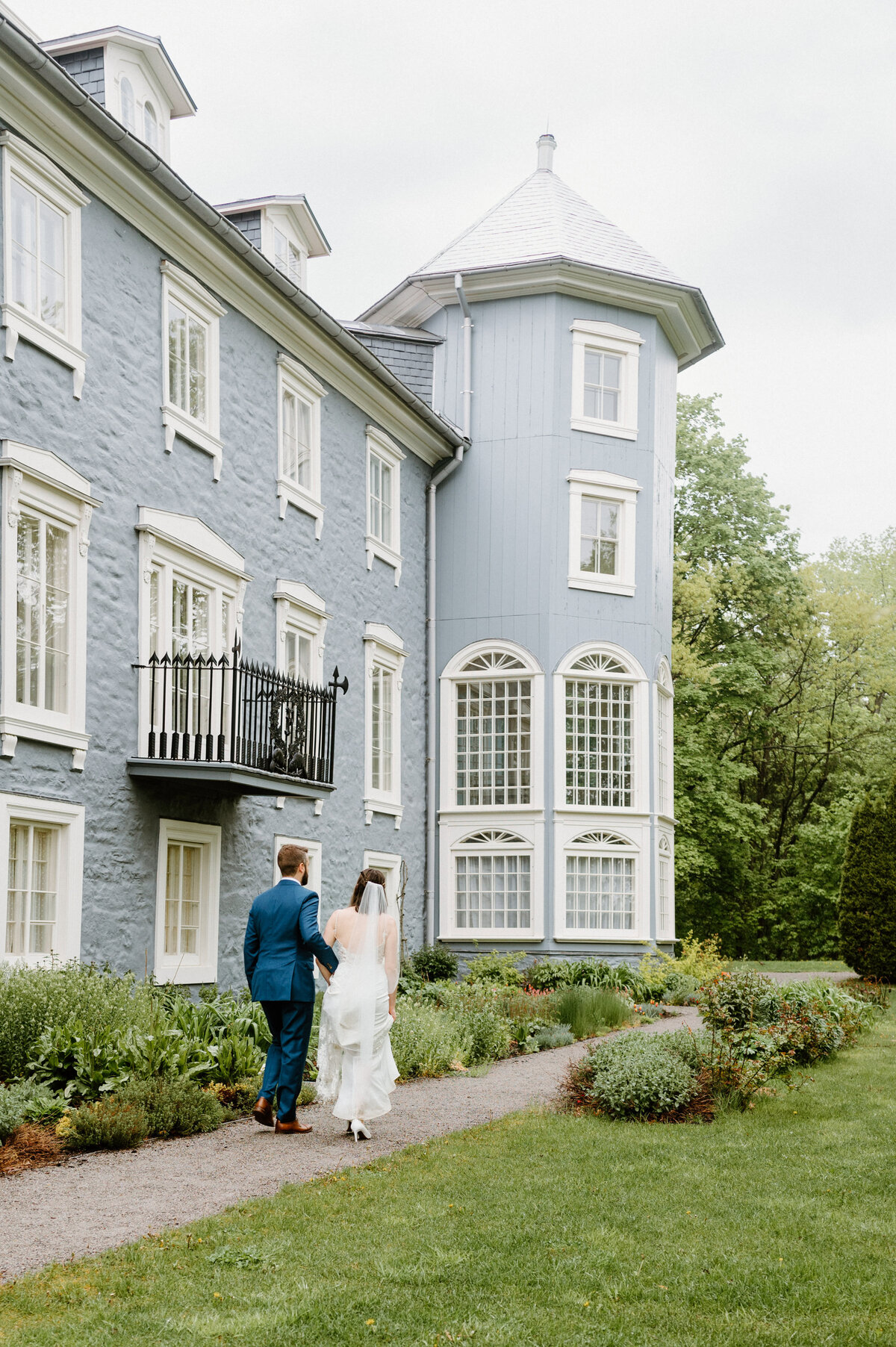 Candid shot of the bride and groom walking through the garden of their wedding venue