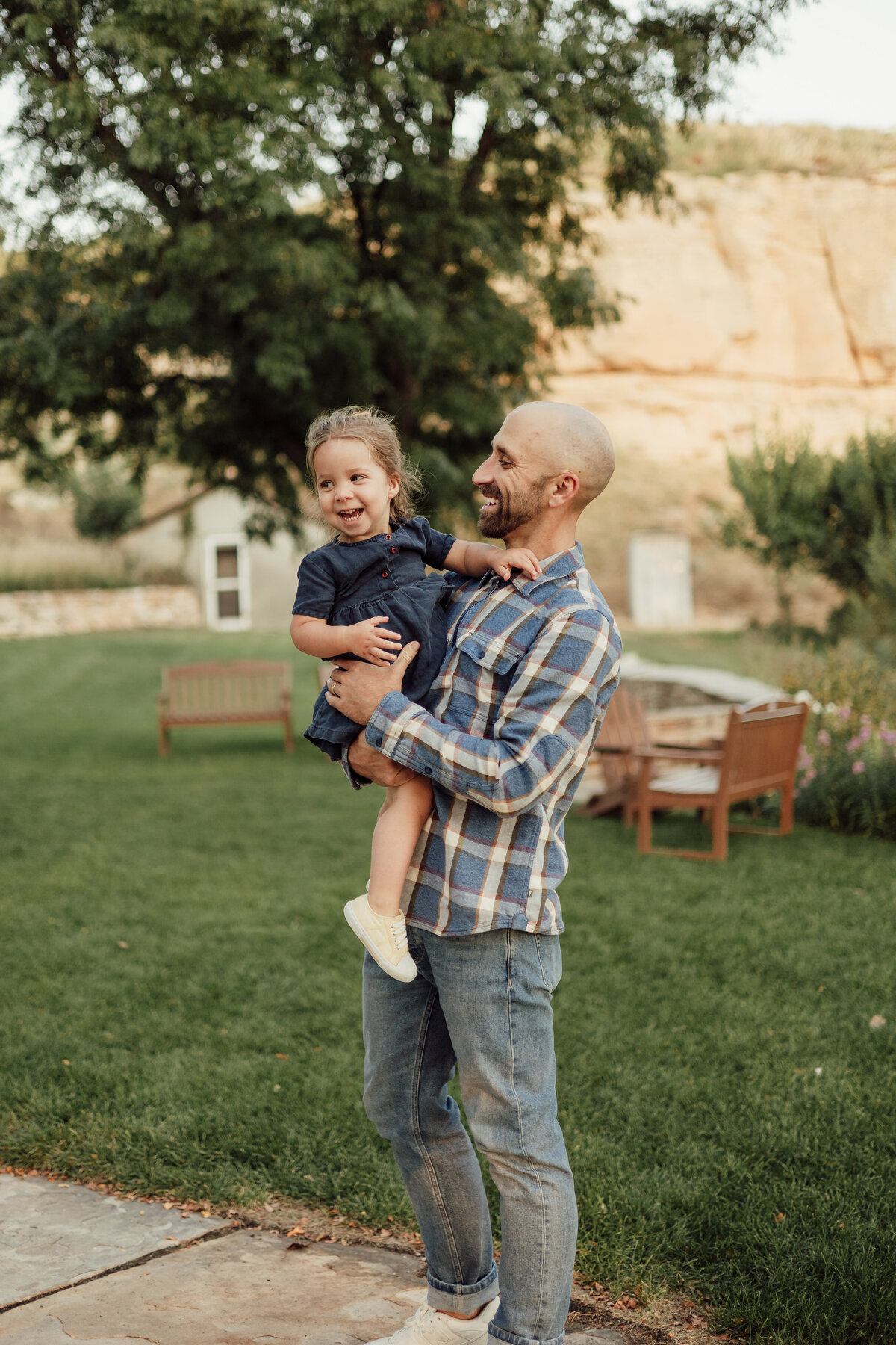 dad holding daughter in blue dress both smiling and laughing in longmont colorado