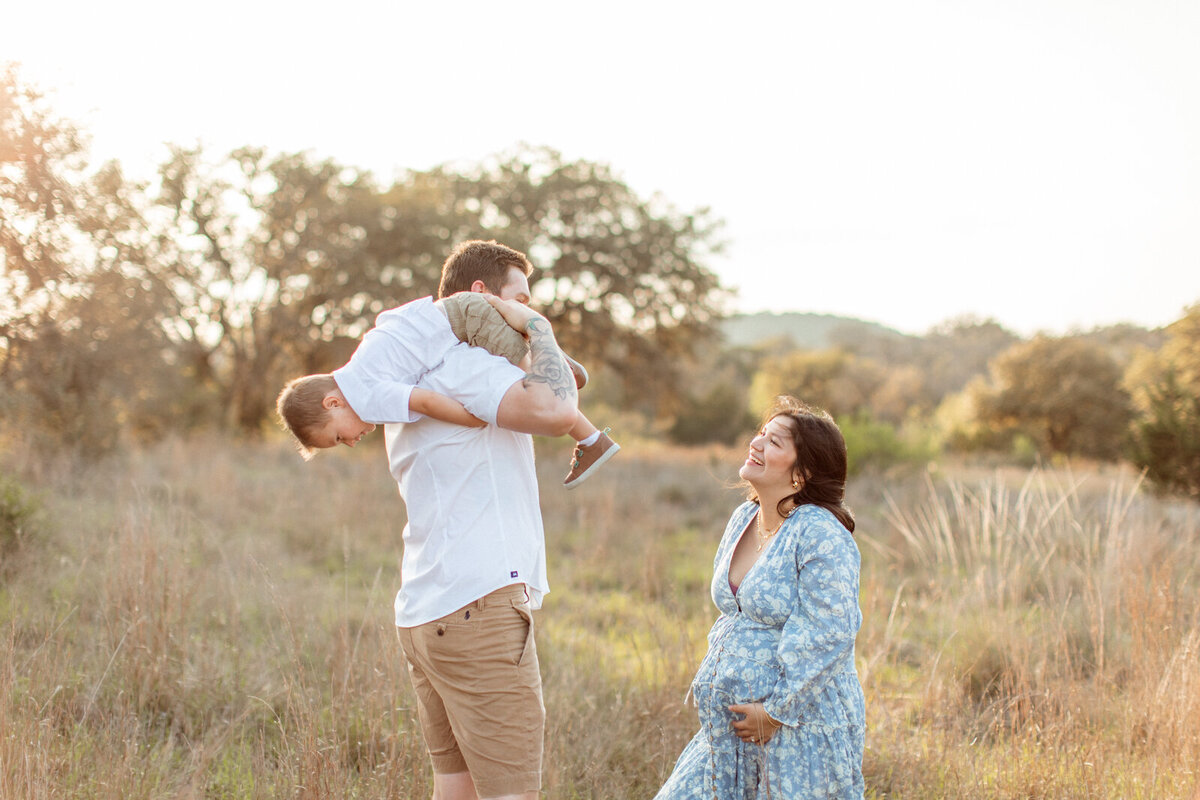 Maternity photo of a pregnant woman with her family in a field, photographed by San Antonio family photographer Sara James.