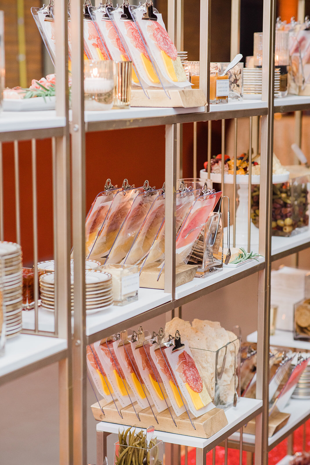 image of charcuterie on miniature clear clipboards on a bookcase display at Willowbrook wedding venue