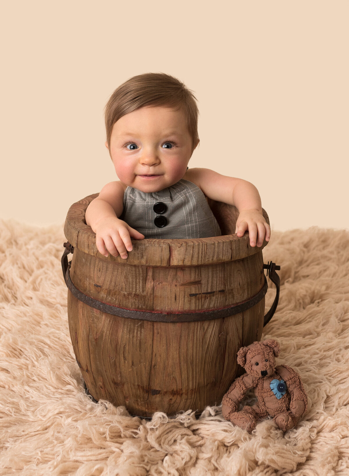 Adorable baby boy in a bucket with brown fury background