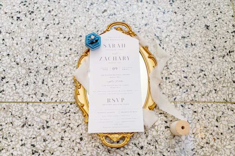 Beautiful flay lay of the wedding invitation with the bride and grooms rings.