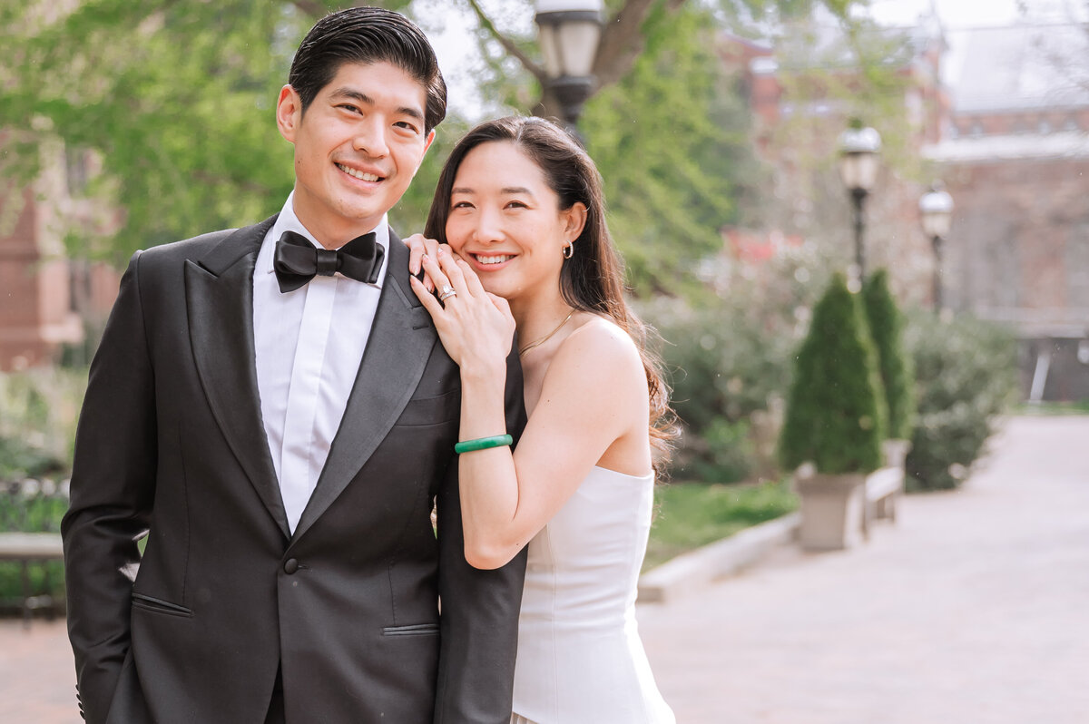A smiling newly engaged Asian couple in a warm green park in the springtime enjoying their Raleigh wedding photography session with JoLynn Photography