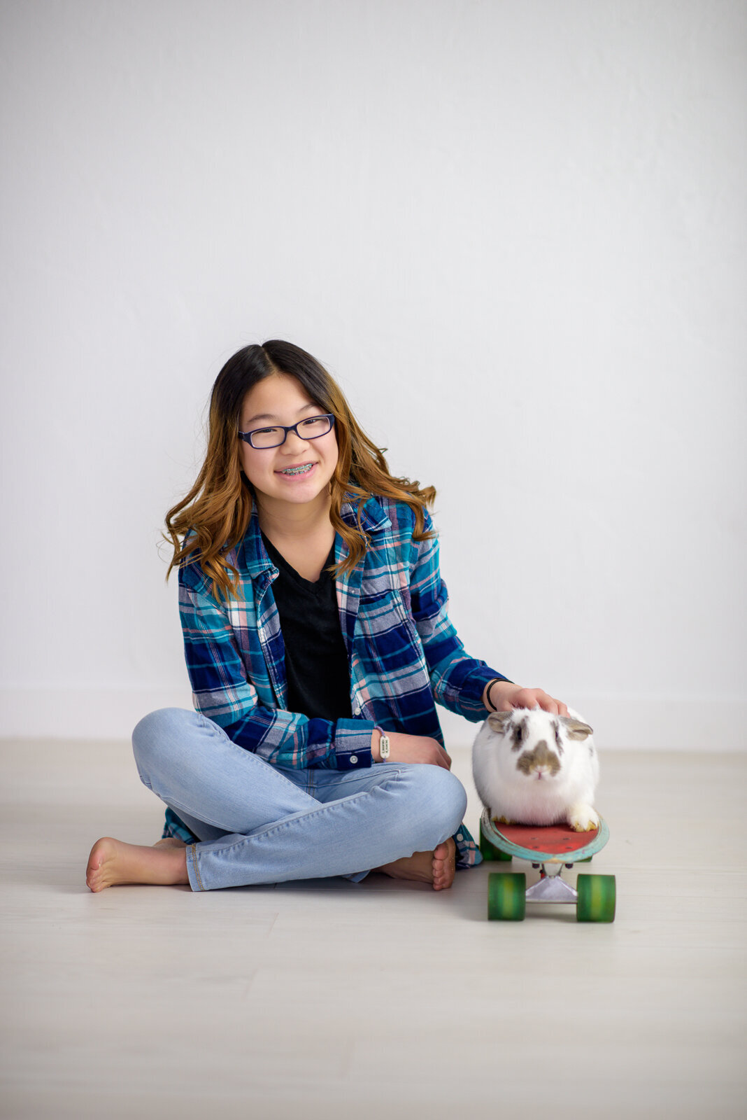 Tween girl with bunny on a skateboard in Boise photo studio.