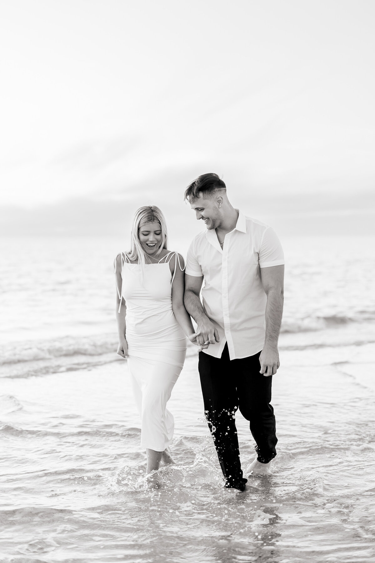couple holding hands and walking in the ocean by sarasota fl wedding photographer