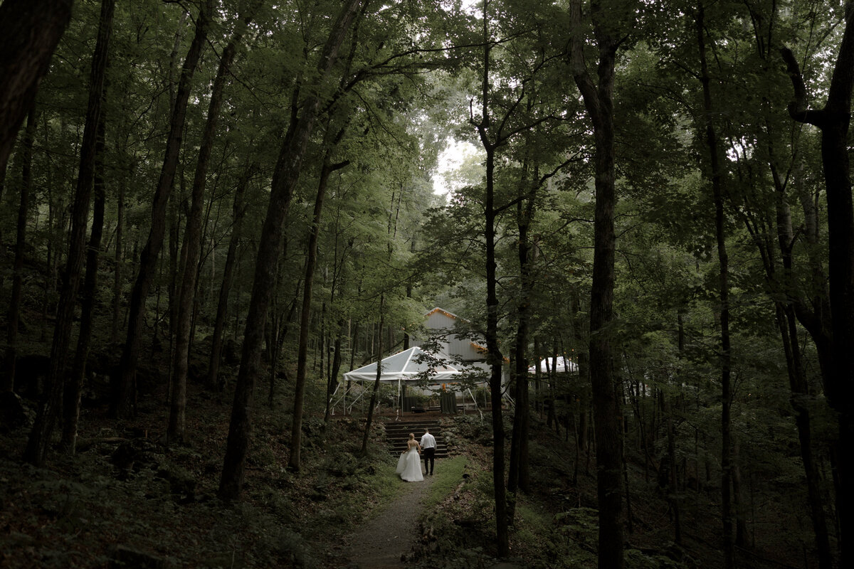 bride and groom standing on cliff with mountains in background