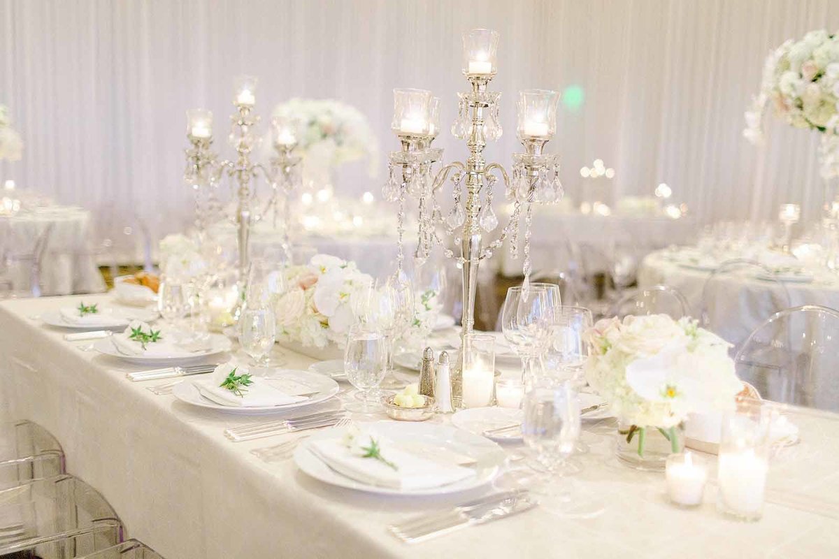wedding centerpiece of crystal candelabras, white flowers, clear lucite chairs
