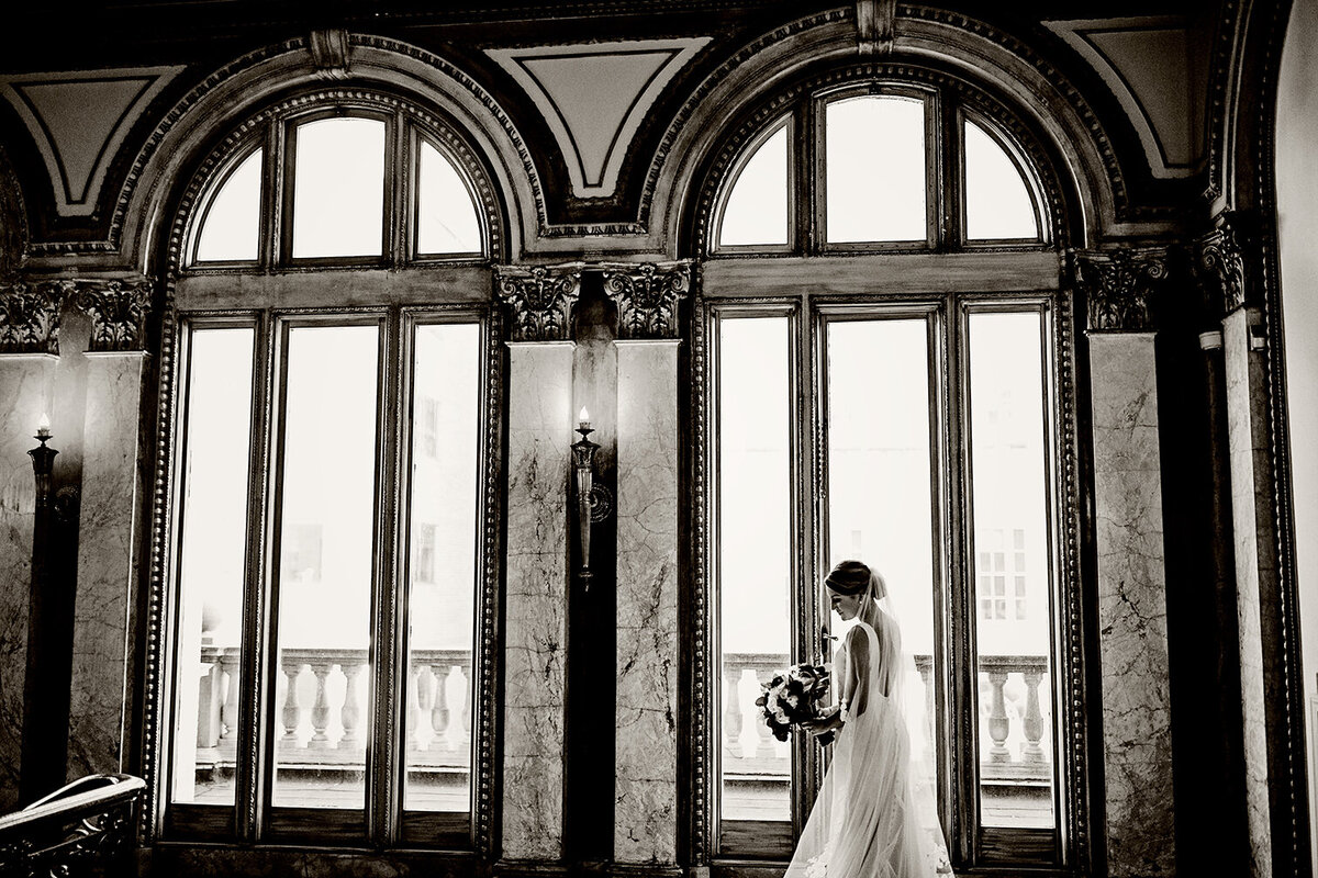 A bride poses in front of windows at Providence Public Library
