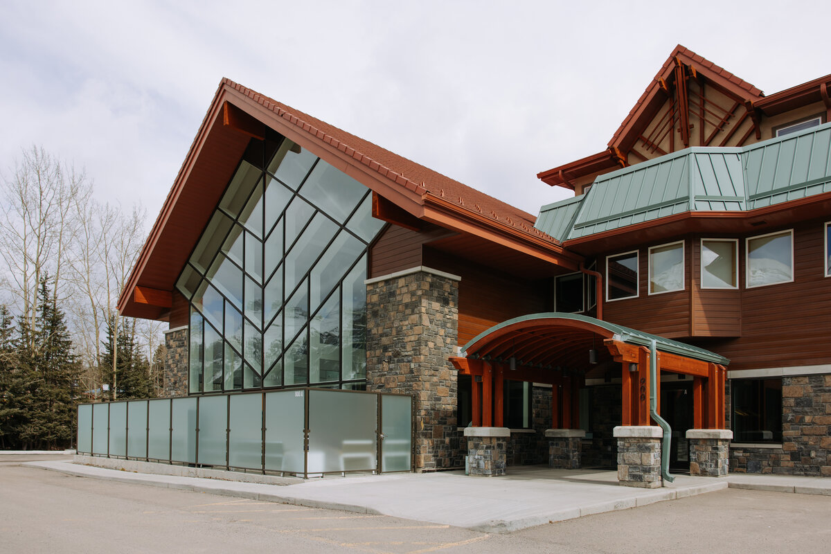 Modern mountain-inspired exterior of The Gem Event Centre in Canmore, Alberta, featuring striking glass architecture, stone accents, and views of the Canadian Rockies.
