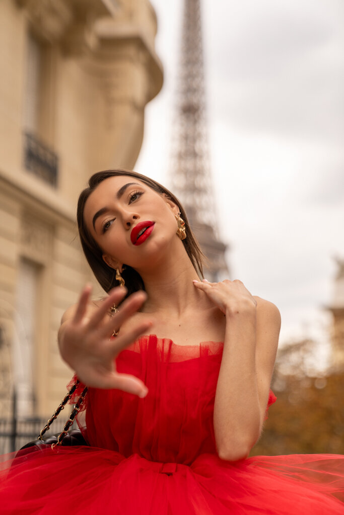 Elegant portrait session close up of brunette woman in red dress and lipstick with Eiffel Tower backdrop