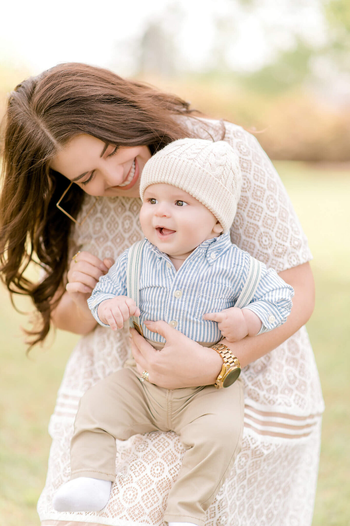 A gorgeous brunette mother looks sweetly at her young baby as he smiles.