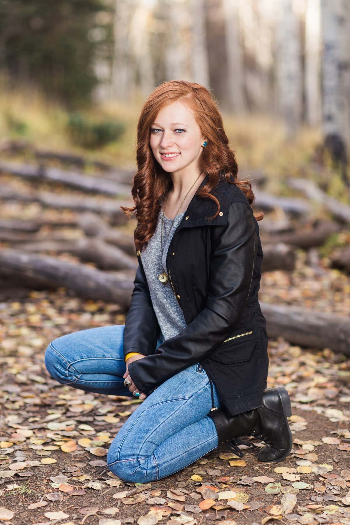 Senior girl squatting in pose in aspen trees near Brighton Ski Resort in Utah.